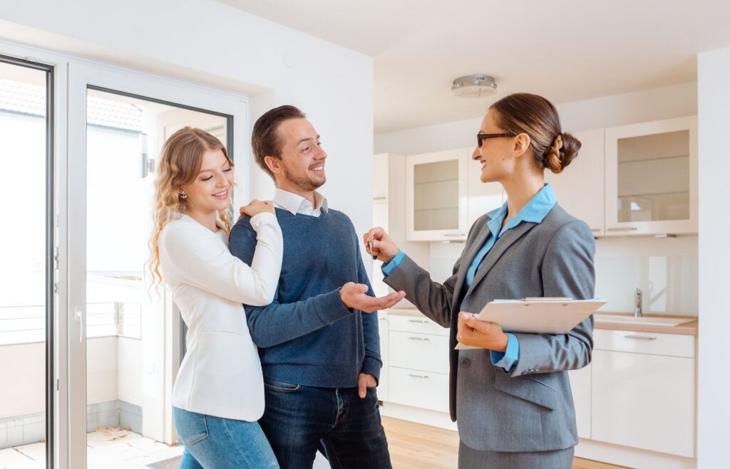 Cheerful realtor giving house key to the buyers or tenants.