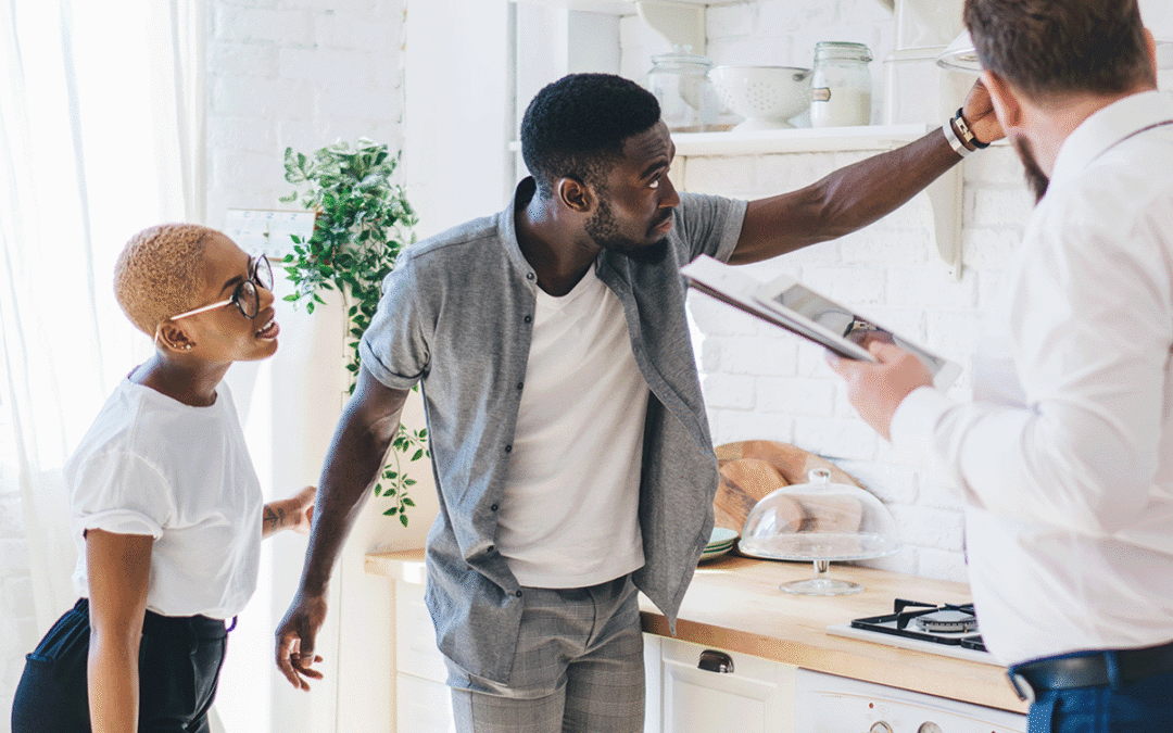 A young couple inspects the kitchen of a rental with a landlord.