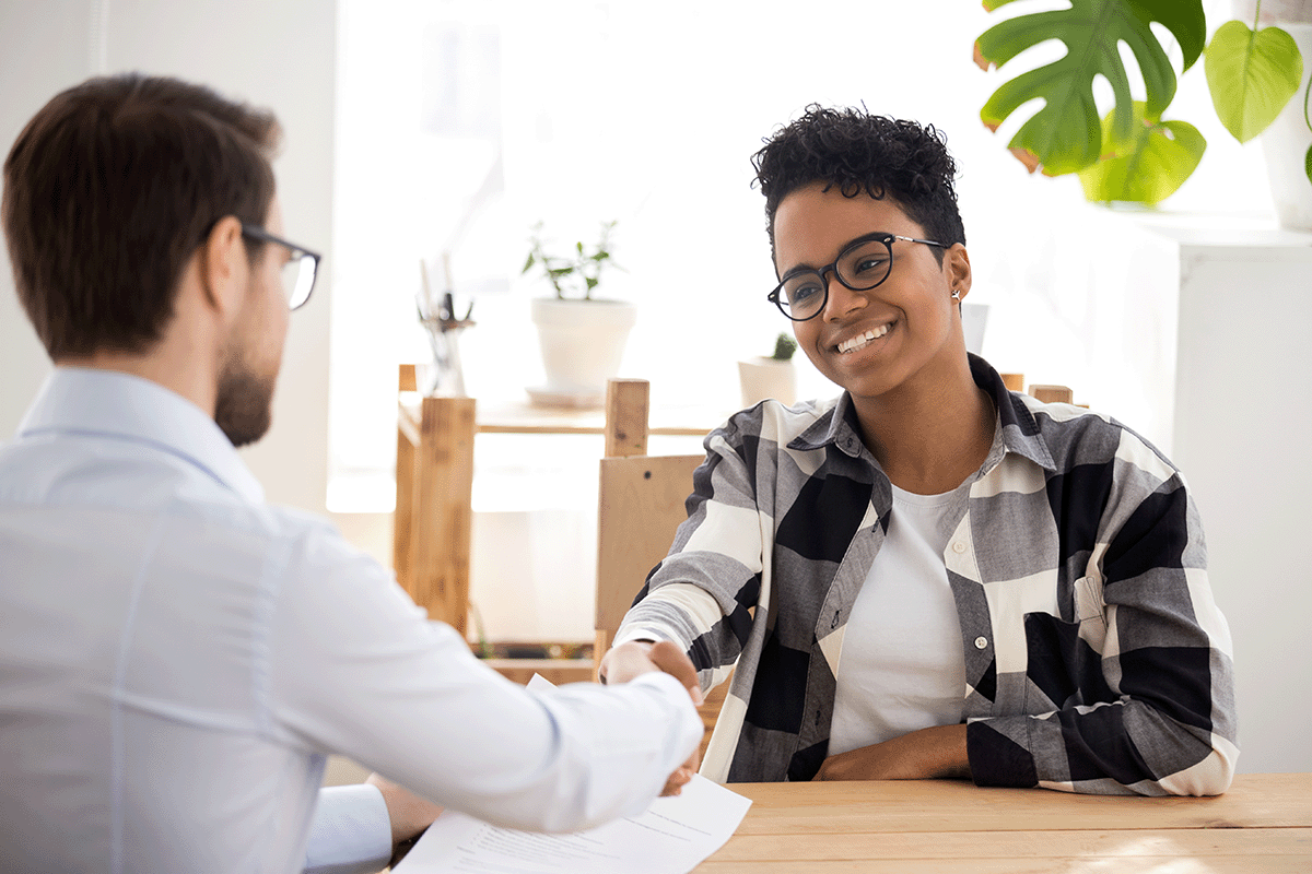 A young renter shakes hands with a landlord.