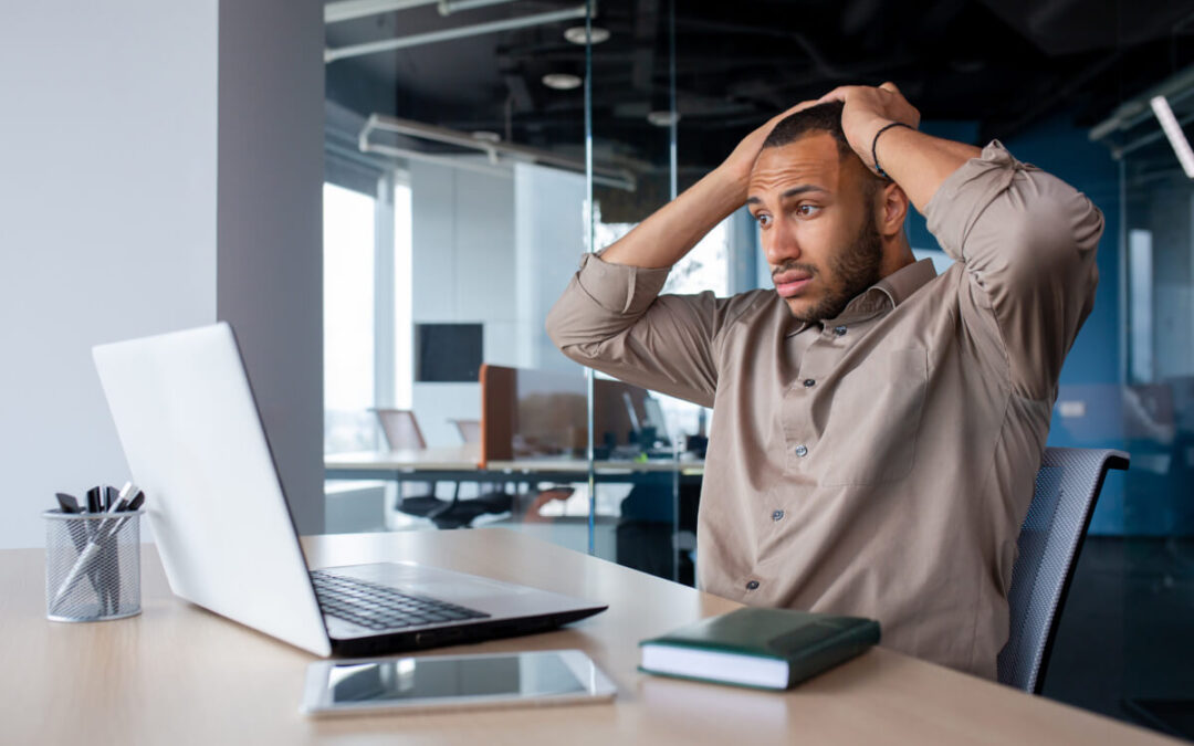 A frustrated man looks at something on his computer.