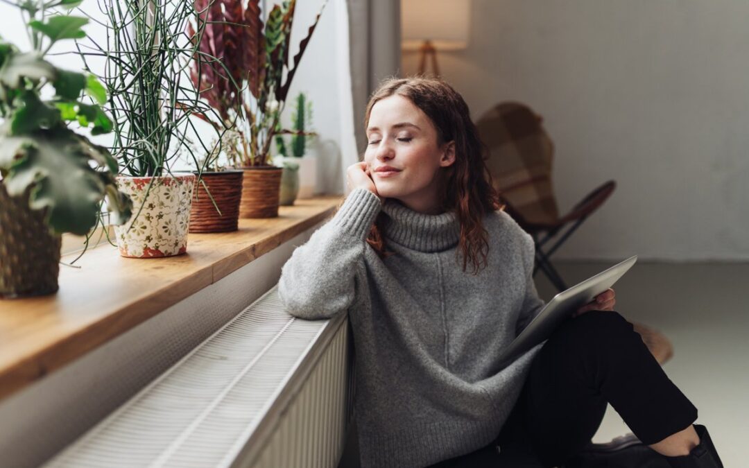 Renter wearing warm sweater lounging by living room window.