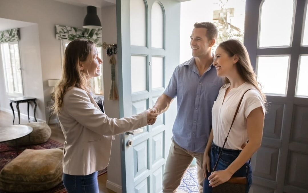 A young couple shakes hands with a private landlord.