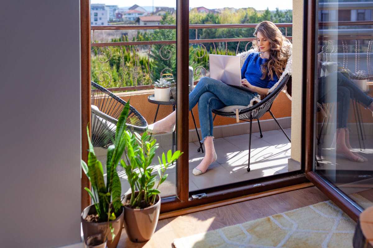 Renter works on her computer on her apartment balcony.