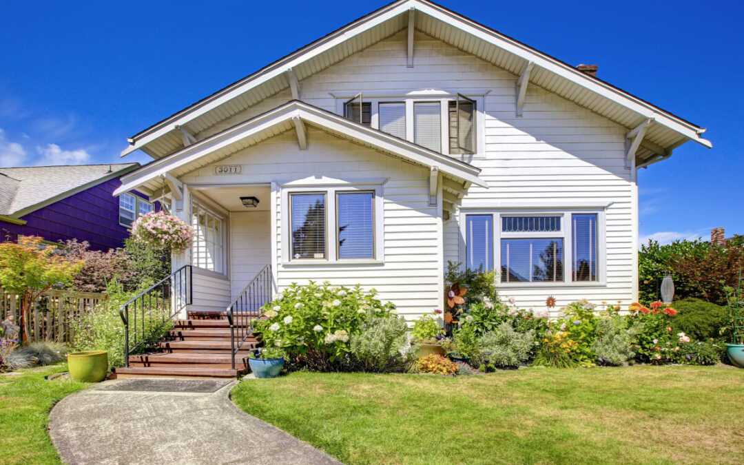 A garden planted in front of a white house.