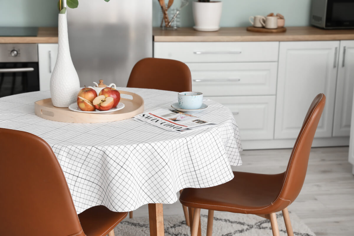 A white and gray gingham tablecloth on a round kitchen table.