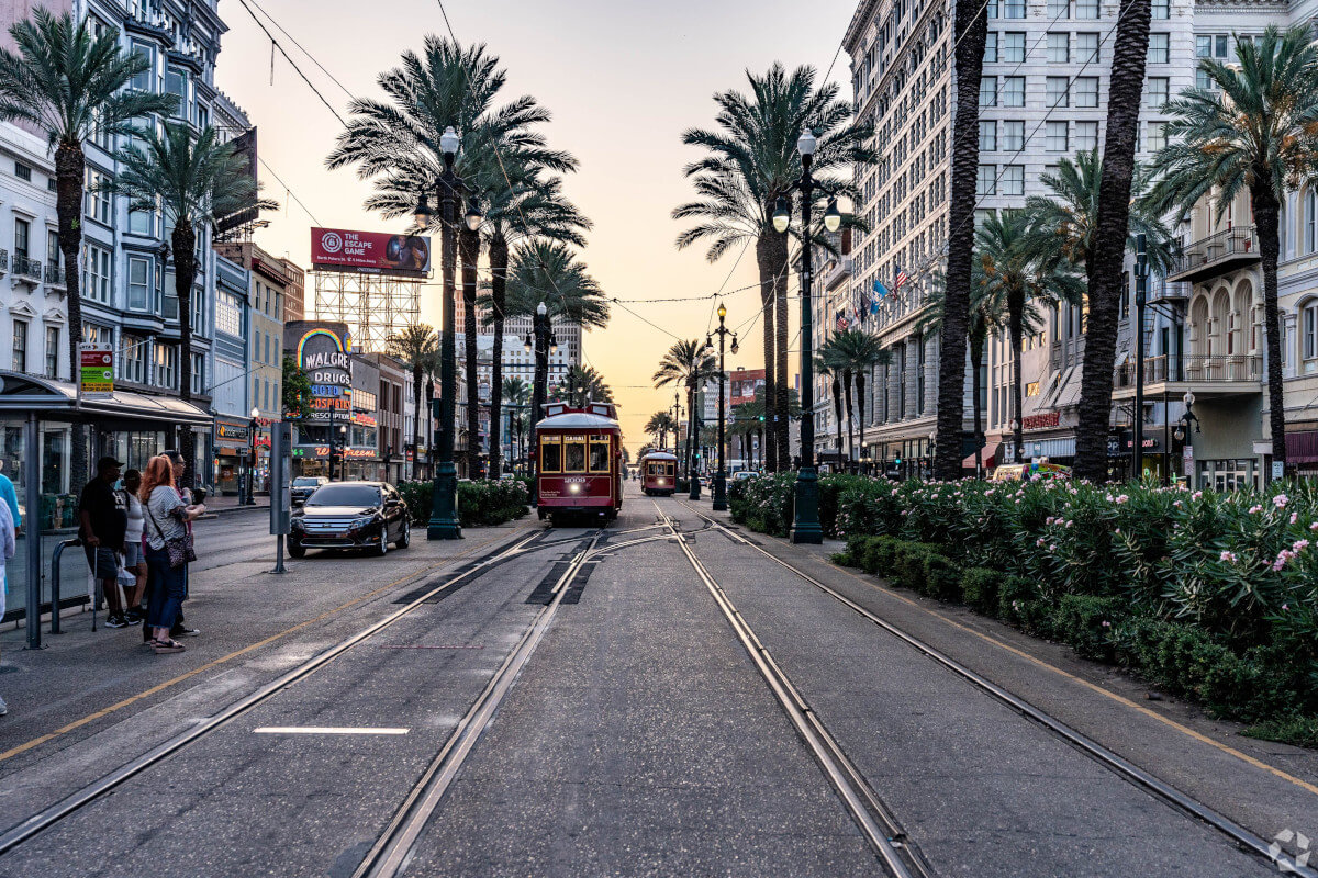 Two red streetcars drive down a street in the French Quarter.