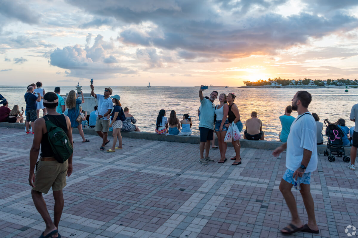 Visitors in Key West take photos of the sunset over the water.
