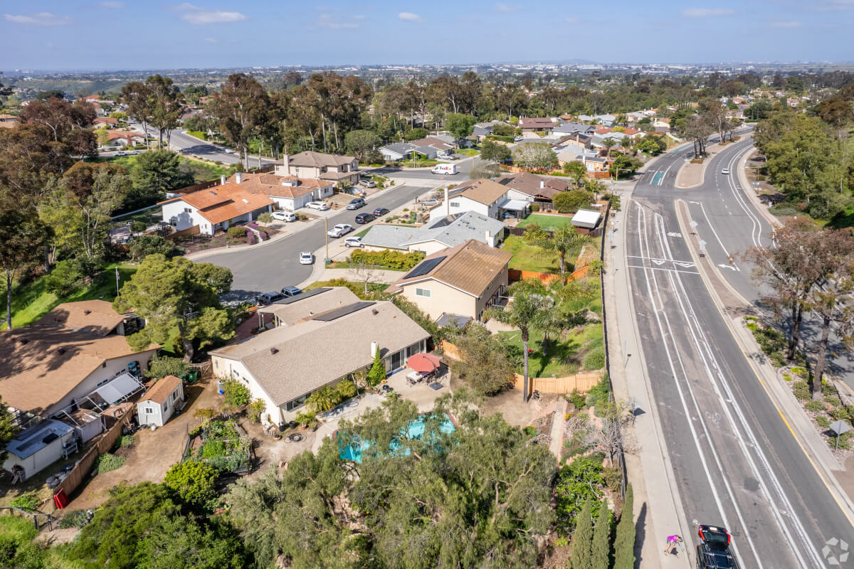 Tierrasanta community with mature trees and single-family homes near a main road, emphasizing a tranquil, centrally located San Diego neighborhood.