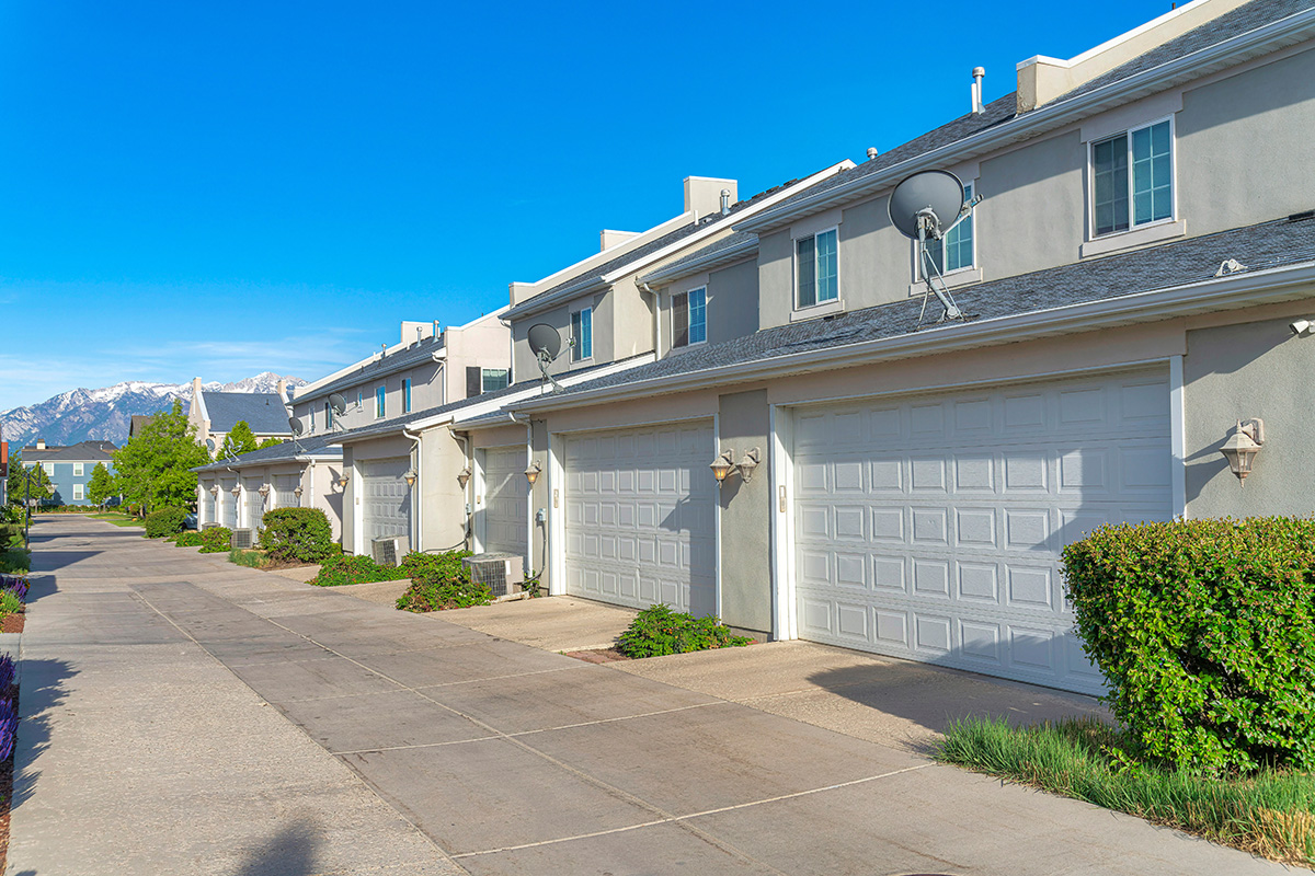 Townhomes with attached garages and concrete driveways with mountains in the distance.