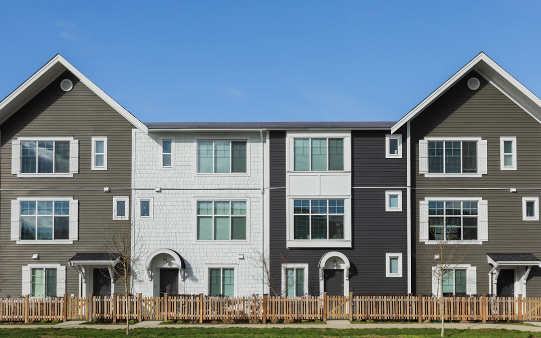 A shot of four gray townhomes on a quaint residential street.