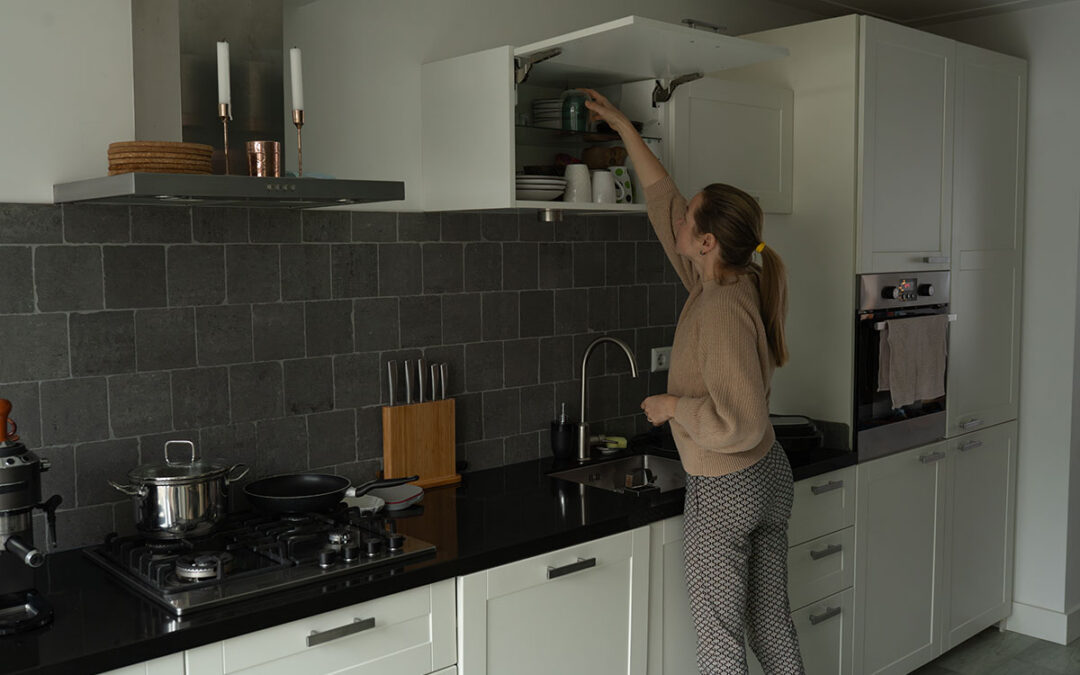 Renter organizing her kitchen cabinets to maximize storage space.
