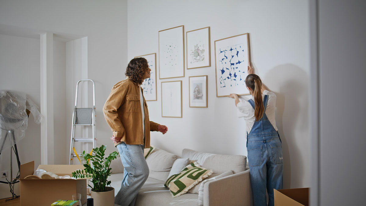 Renters hanging up lease-friendly decor in their new apartment.